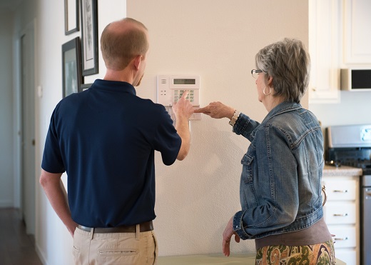 A technician helping a homeowner set up her home security system.