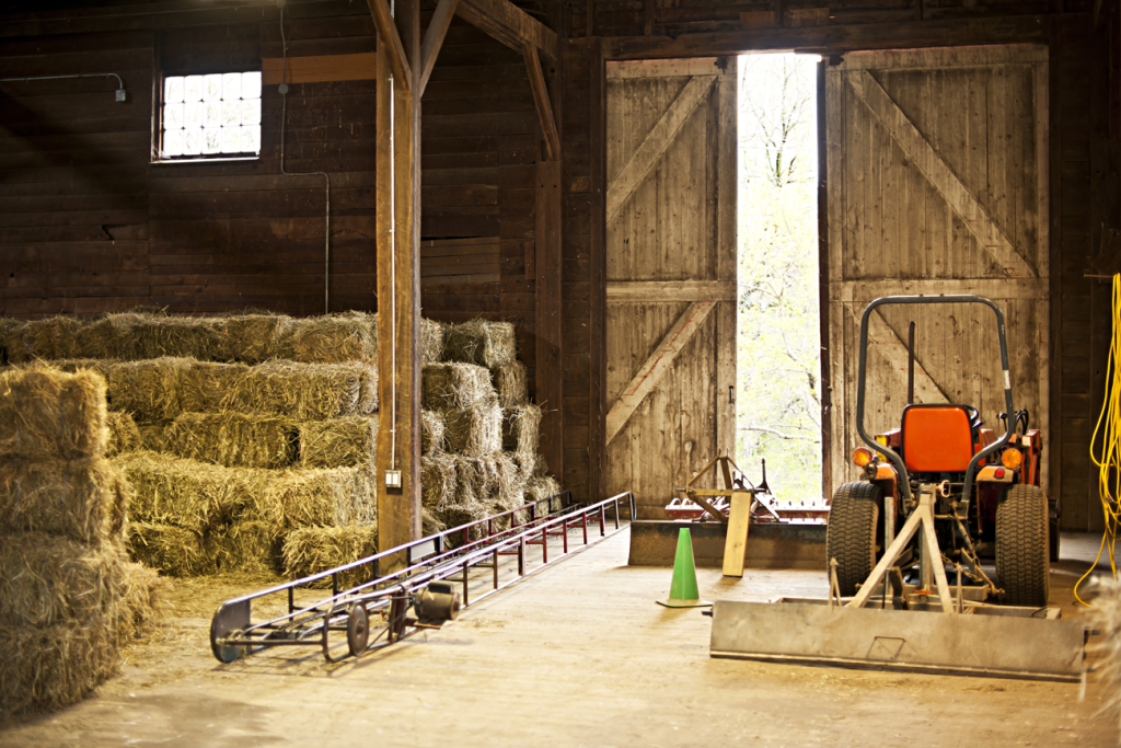 farm equipment sits in a barn with hay