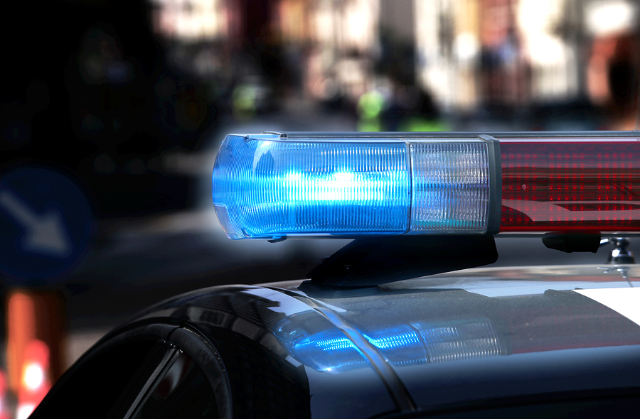 Police patrol car with flashing lights and siren on during the night raid against crime