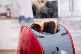 Close-up Of Burnt Toast Coming Out Of Toaster In Kitchen