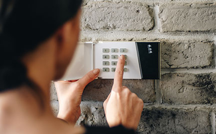Homeowner attentively setting a security code on a digital keypad of a home security system.