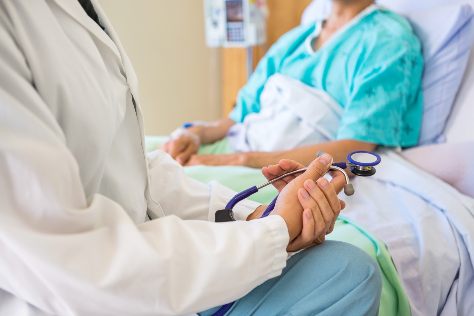 a physician sitting at the bedside of a patient