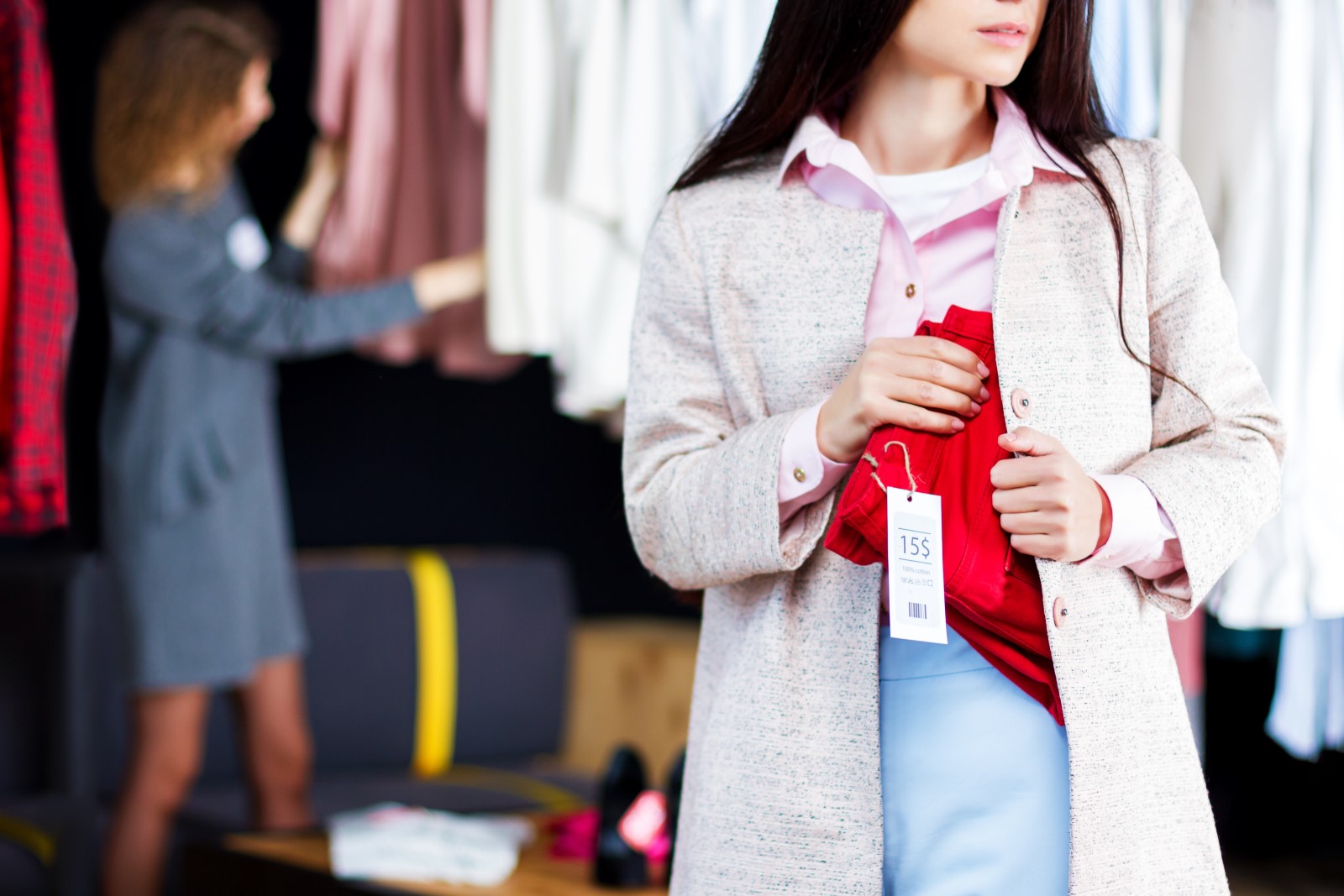 Young woman stealing red jeans in store