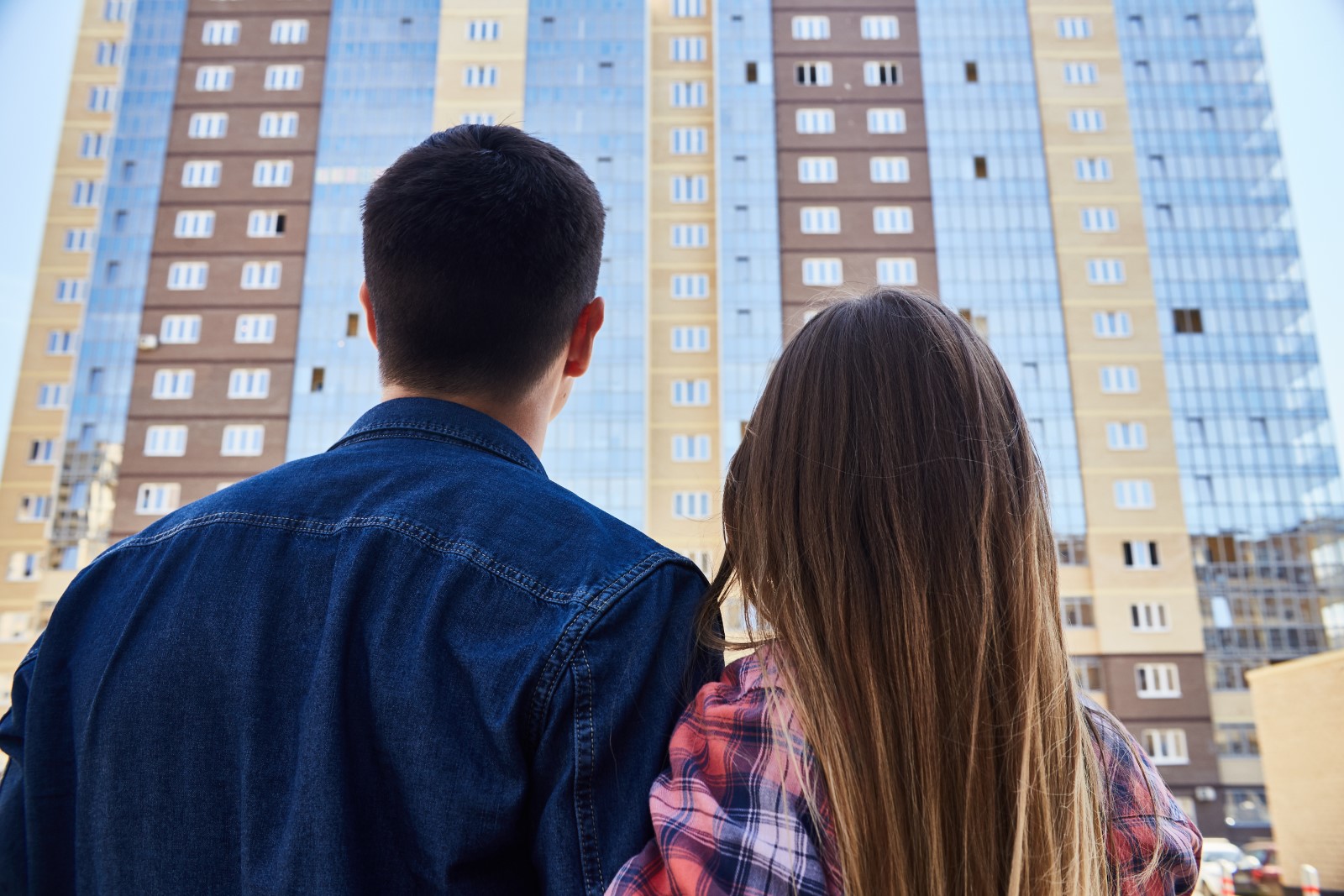 a couple looks up at their new apartment building from the street