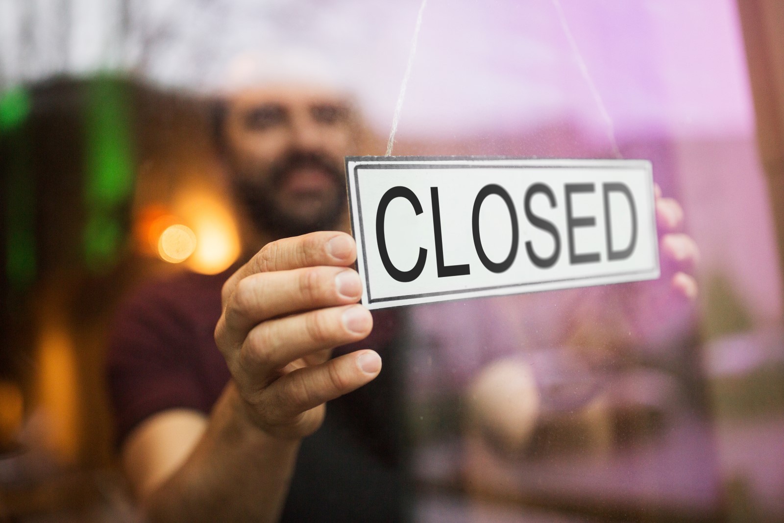 a restaurant worker puts a closed sign on the front door