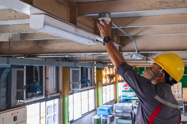 A technician installs a fire alarm as part of a contractor security system.