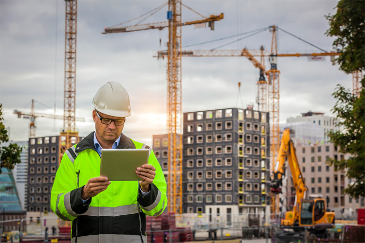 A construction manager checks on another site using an online contractor security system.