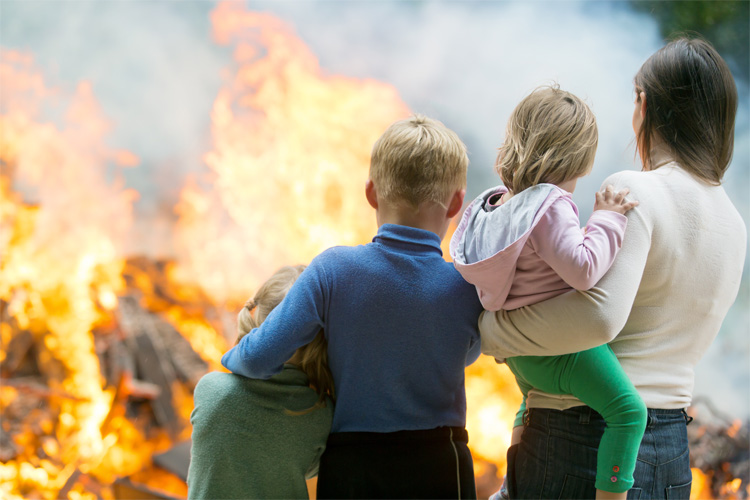 A mother and her children watching their home burn in a fire.