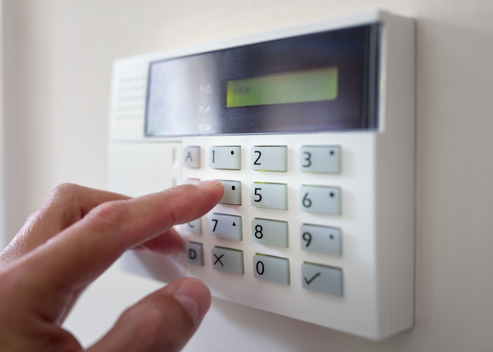 A security alarm technician re-activating an older alarm system.